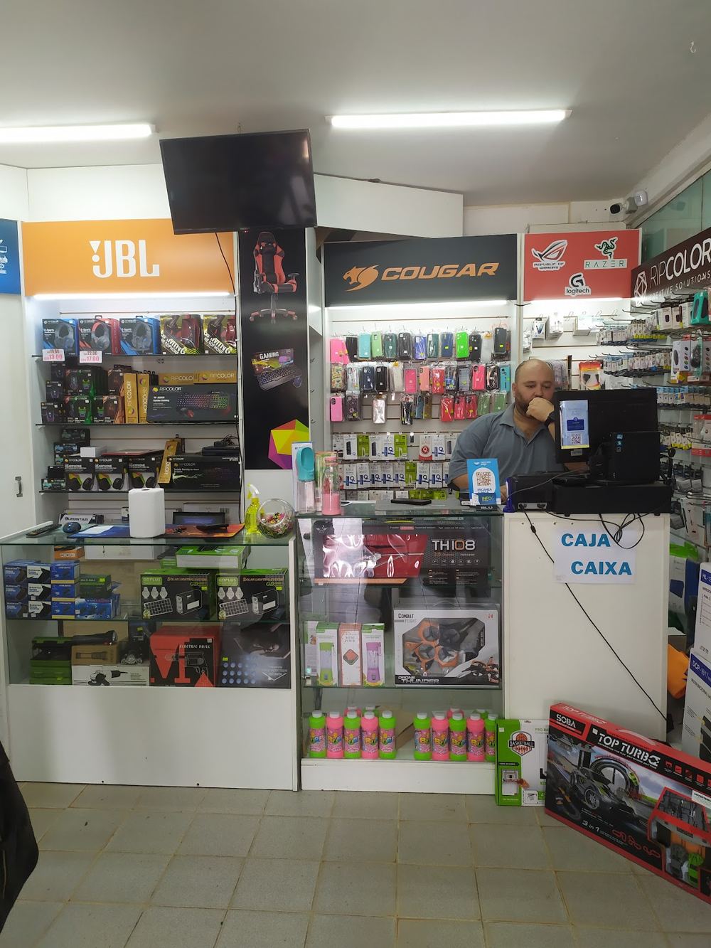 Mostrador de Info Shop con auriculares, teclados, fundas para celulares y otros accesorios en las vitrinas